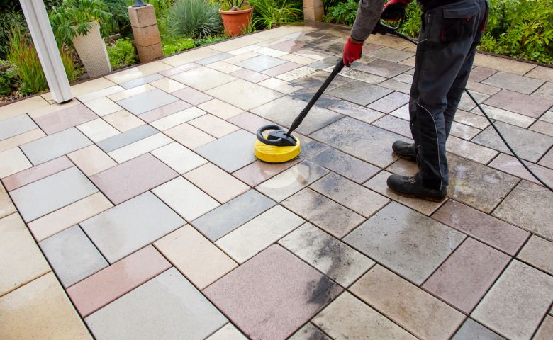 Cleaning stone slabs on patio with the high-pressure cleaner.